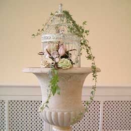 Vintage-style roses and invy in a birdcage for an interesting pedistal arrangement